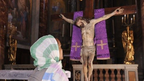 Mulher rezando em frente ao Crucificxo
