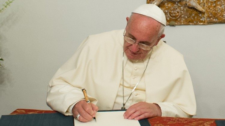 Papež Frančišek podpisuje dokument.