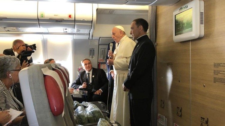 Pope Francis greets journalists aboard the papal plane