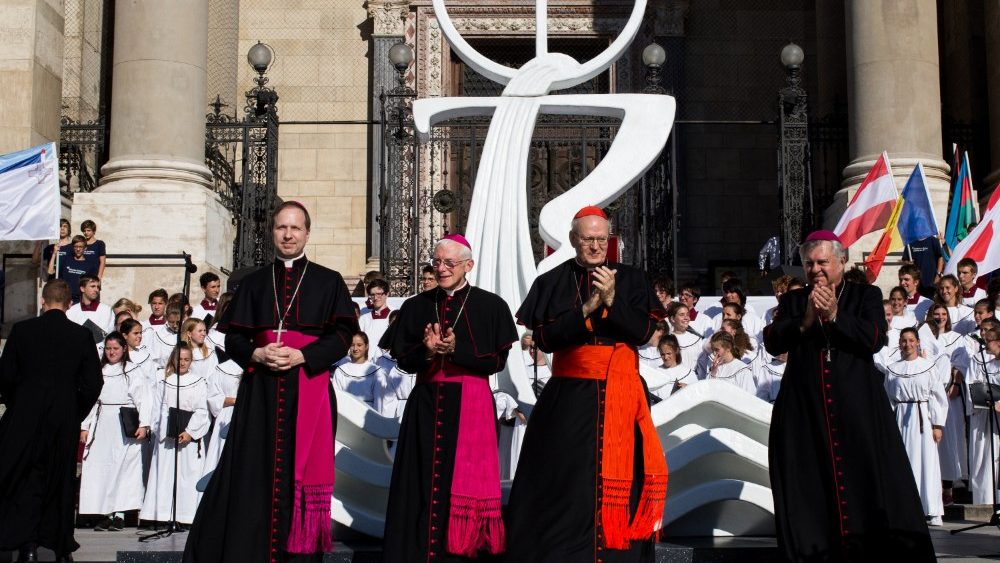 Kardinál Péter Erdő s maďarskými biskupmi pred Bazilikou sv. Štefana, v pozadí emblém MEK 2020