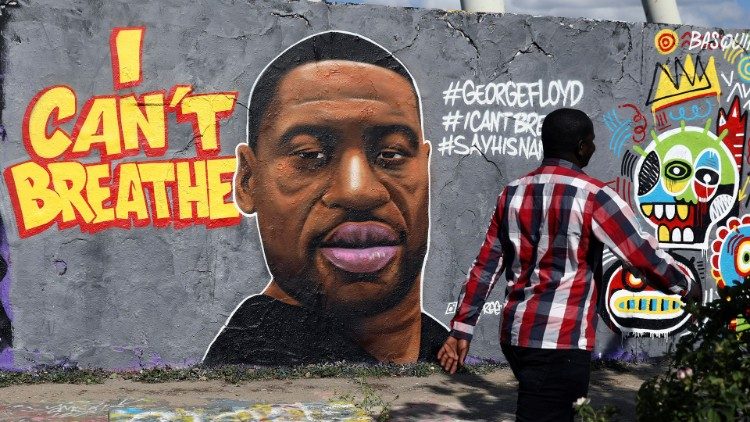 A man walks in front of a mural in honor of George Floyd