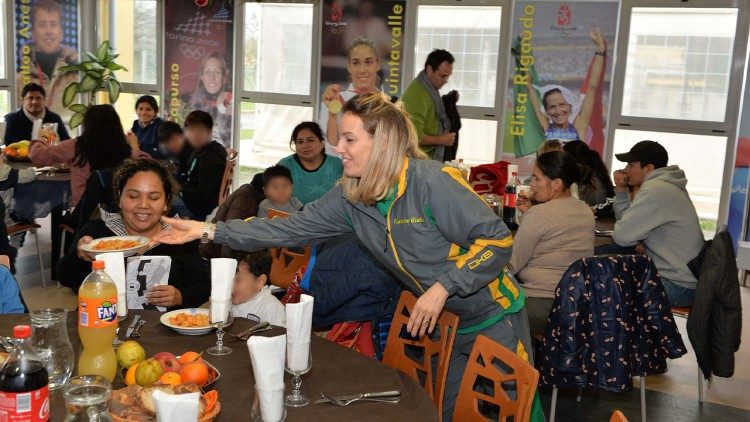 Tania Cagnotto serve ai tavoli il cibo preparato per le famiglie assistite dal Dispensario Santa Marta