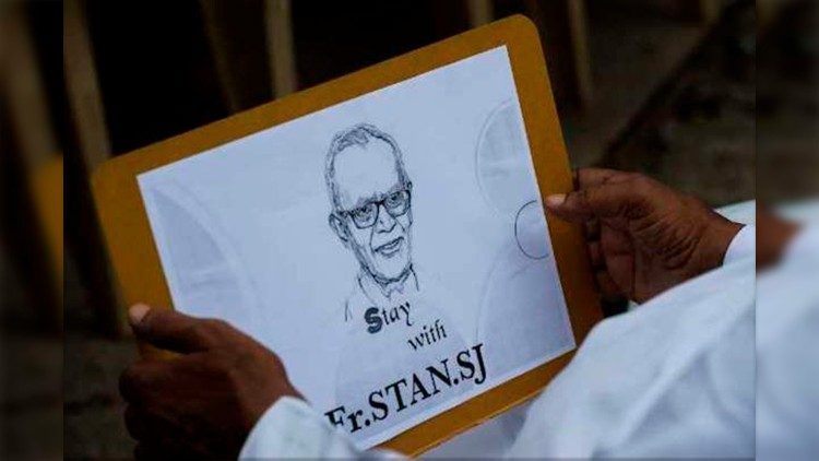 A man holds an image of Fr. Stan Swamy, SJ