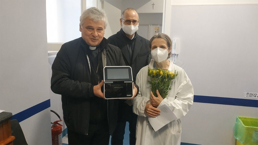 Cardenal Konrad Krajewski con la nueva máquina, junto al doctor Andrea Benassi, presidente Siloe Onlus  y la doctora Lucia Ercoli, coordinadora de la clínica. 