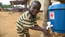 Un niño sonriente se lava las manos en la sede de Cáritas en Liberia.
