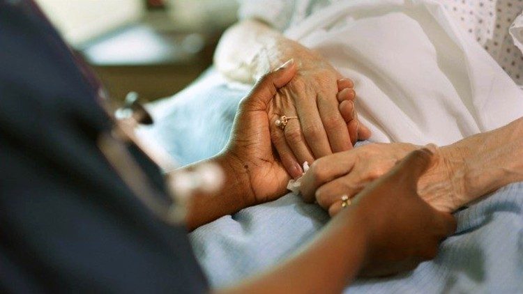 Una enfermera sostiene las manos de un paciente enfermo.