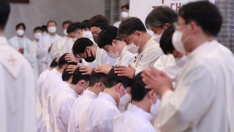 Priests lay hands on the heads of their new priestly brothers