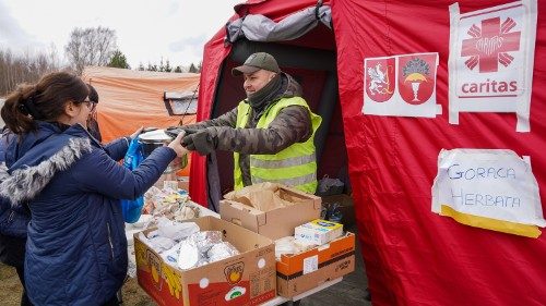 File photo of a Caritas Poland volunteer handing out food aid to a Ukrainian refugee in the early days of the war