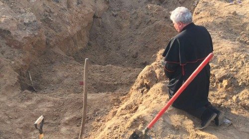 Cardinal Konrad Krajewski kneels at the site of a mass grave in Borodyanka, Ukraine