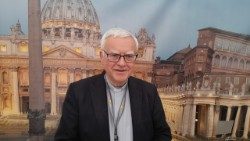 Erzbischof Koch 2022 vor einem Plakat mit dem römischen Petersdom