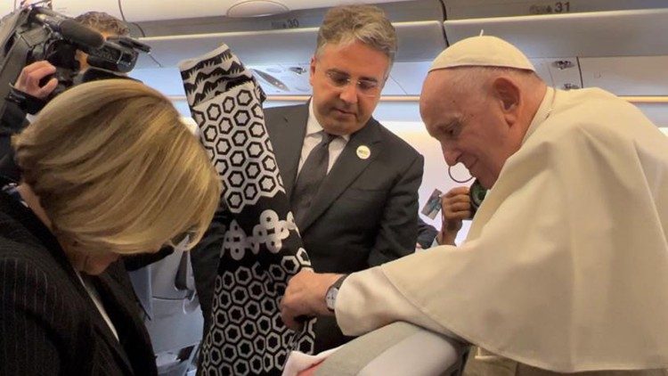 Pope Francis receives a capulana from a journalist aboard the papal plane
