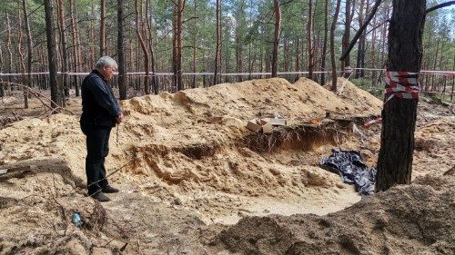 Le cardinal Krajewski en prière devant les fosses communes d'Izioum 