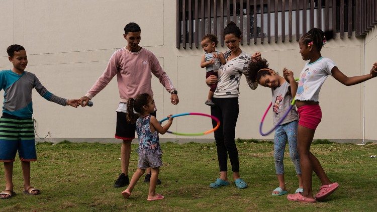 Enzor Figuera, imigrante venezuelano, brinca com os filhos enquanto espera receber formação e encontrar um emprego estável. (@Margherita Mirabella/Archivio GSF)