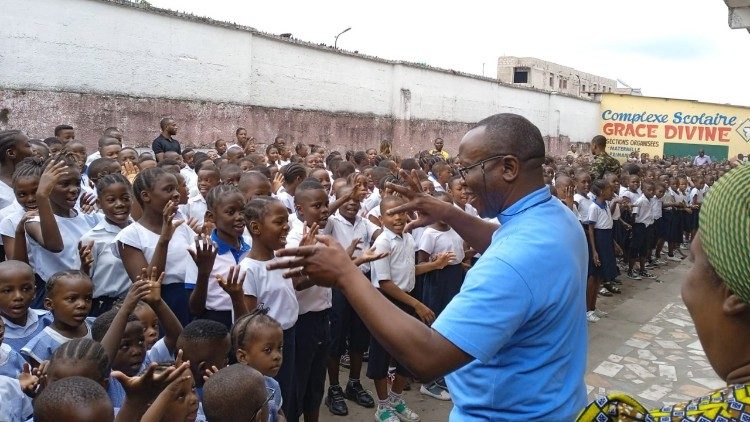 Don Robert Kasereka Ngongi, presidente dell'Opam, con gli studenti di una scuola nella Repubblica Democratica del Congo sostenuta dall' Opera per la promozione dell'alfabetizzazione nel mondo