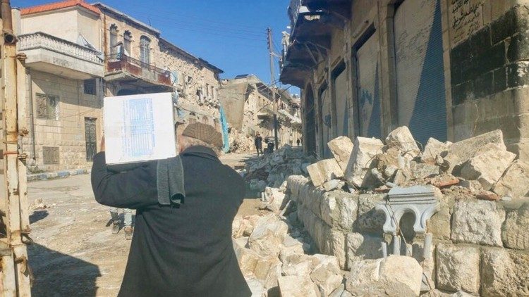 Terremoto in Siria un uomo porta un pacco alimentare 