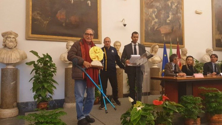 Alla presentazione della Maratona di Roma 2023 al Campiodoglio, l'artista Bandfeldt Rosada (a sinistra) presenta la Coppa degli Ultimi da lui realizzata. Al centro, il presidente di Athletica Vaticana Giampaolo Mattei