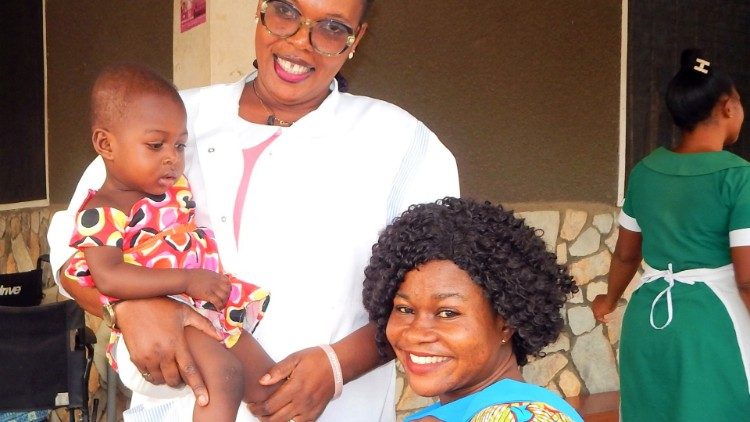  Uma profissional de saúde com mãe e filha após os procedimentos de controlo e vacinação