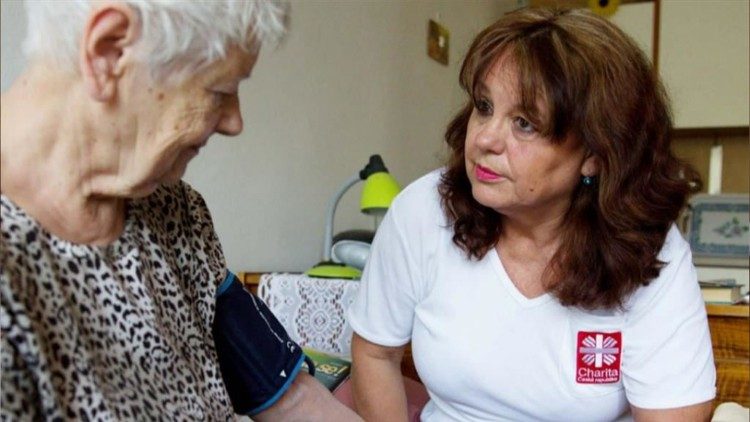 A Caritas member offers care to an elderly person