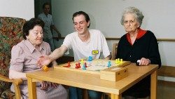 Ein junger Pfleger spielt ein Brettspiel mit zwei Seniorinnen
