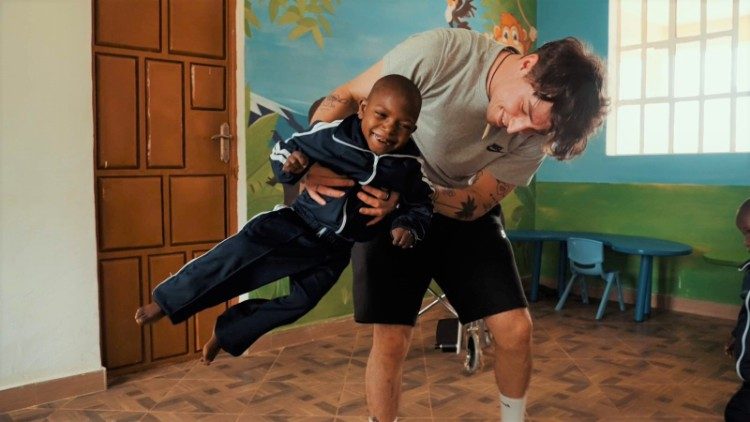 Um voluntário brinca com uma criança deficiente na missão de Laare