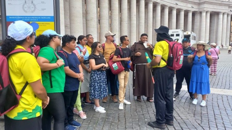 Monsignor de Assis (a destra col cappello) parla ai giovani prima della visita alla Basilica di San Pietro