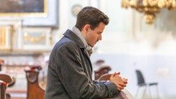 Ein junger Mann ist im Gebet vertieft