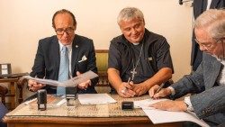 l cardinale Krajewski firma il protocollo d'intesa con il professor Profita (a sin.), rettore dell’università UniCamillus, e il dottor Nicolò Vinciguerra (a destra), della clinica “Madonna della Fiducia”