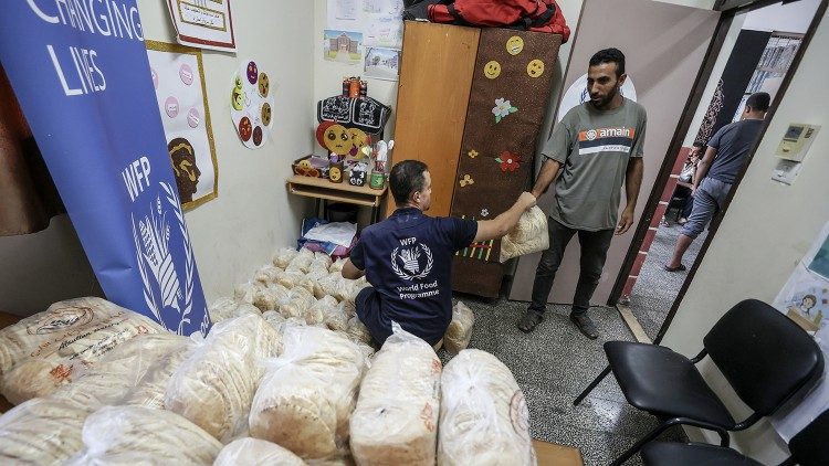 Un operatore del Programma Alimentare Mondiale (World Food Programme) distribuisce pane alla gente di Gaza