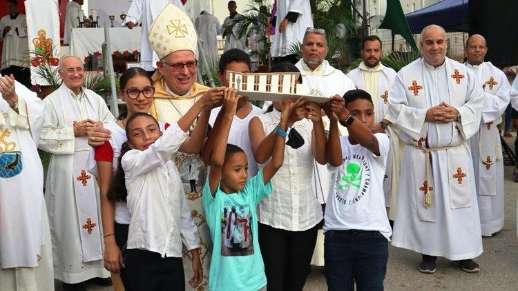 Bischof Raúl Biord Castillo mit Kindern, die ein Modell der neuen Kirche zeigen. @ Kirche in Not