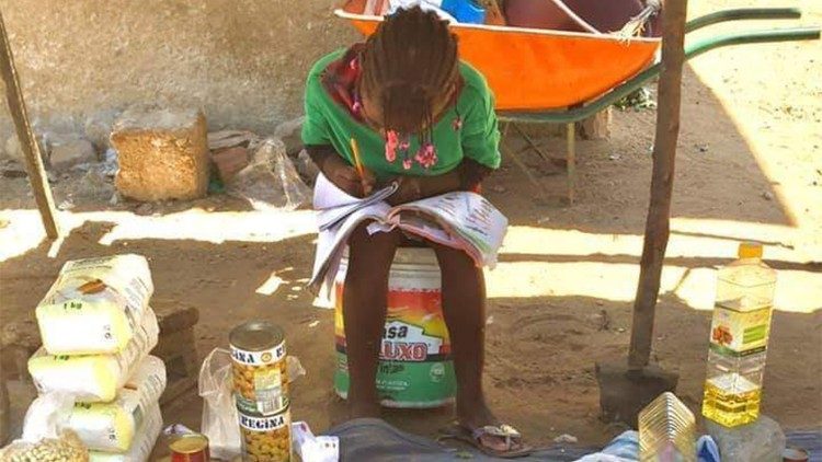 Menina estudando enquanto vende mercadorias na rua