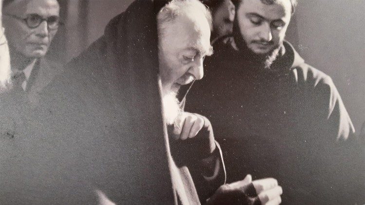 Padre Pio mentre benedice un rosario