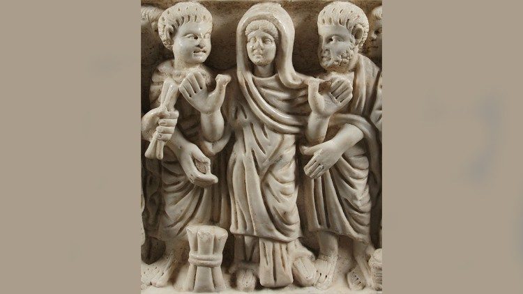 Image du sarcophage de Marcia Roumanie Celsa à Arles, France. La défunte est dans une attitude d'orans avec un paquet de parchemins à ses pieds et des figures d'« apôtres » face à elle. (Musée de l'Arles Antique, sarcophage de Marcia Roumanie Celsa, ©R. Bénali, L. Roux)