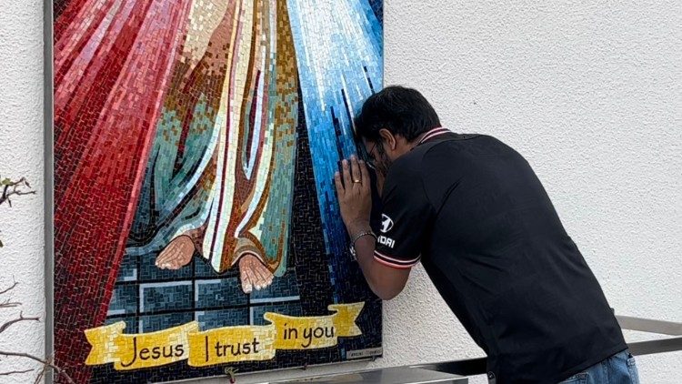 Un fedele in preghiera davanti all'immagine a mosaico di Gesù Misericordioso, sulla facciata della catttedrale di Abu Dhabi