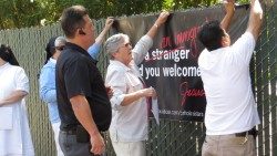 Sr. Elaine (Mitte) und ihre Freunde hängen an einer belebten Straße ein Transparent auf, um ihre Unterstützung für Einwanderer zu zeigen. In einer leichten Abwandlung des Jesuswortes steht dort geschrieben: „Ich war ein Einwanderer und ihr habt mich aufgenommen“.