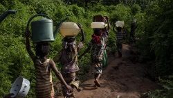 Kinder in Afrika balancieren Wasser auf dem Kopf.